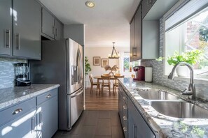 A modern kitchen with a built-in refrigerator, a dining area with a table and chairs, and a large window providing natural light.