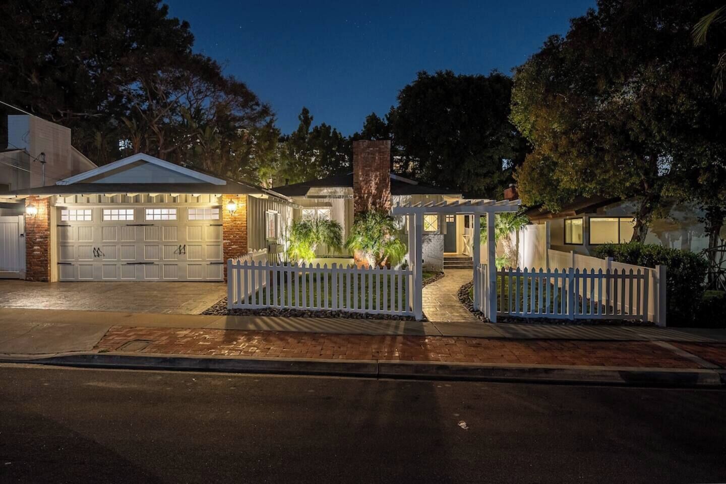 A residential property with a garage, a covered porch, and a white picket fence.