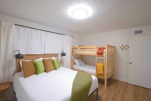 A room with a bunk bed, a single bed, and a desk.
