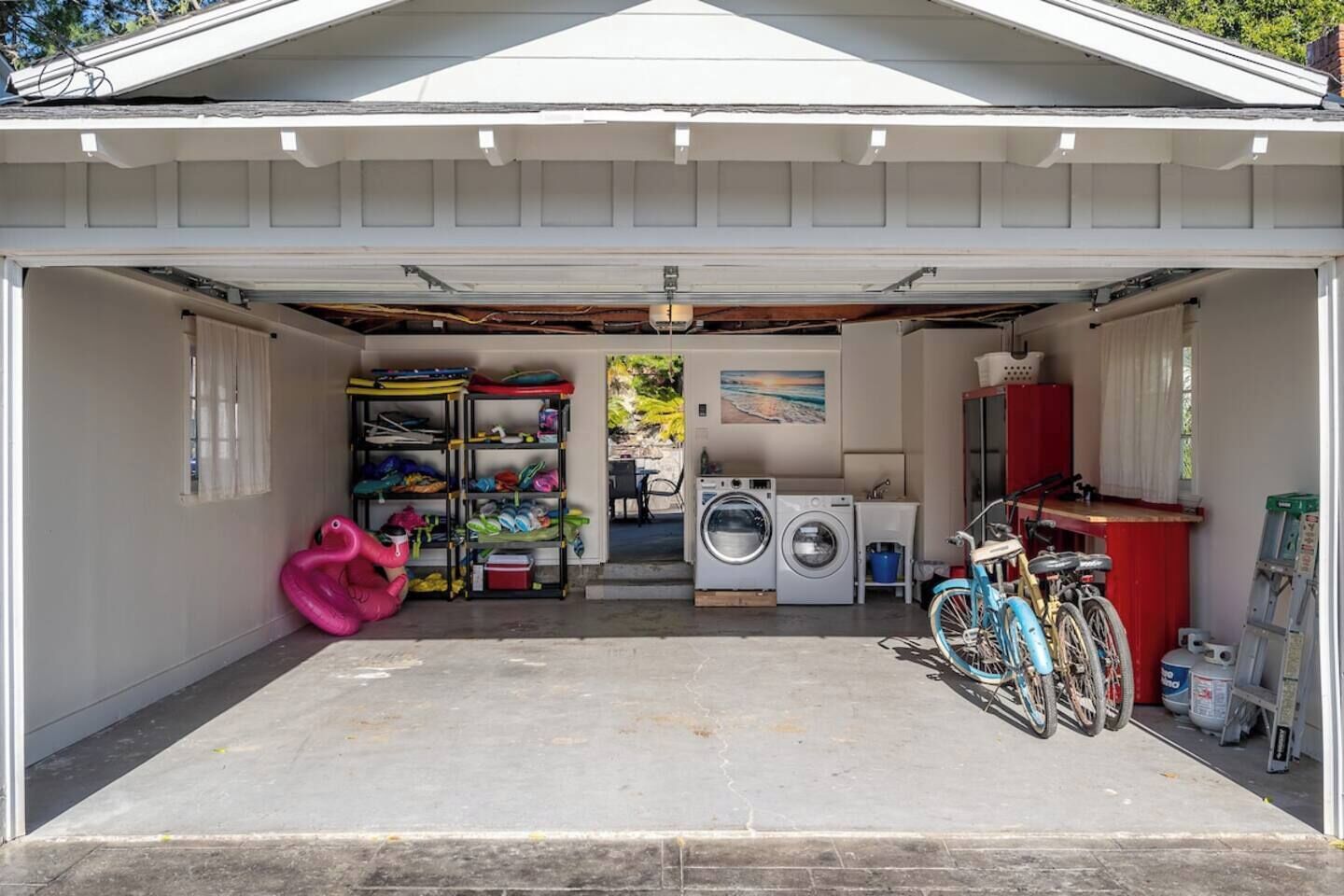 A garage with a washing machine, a bicycle, and various storage shelves.