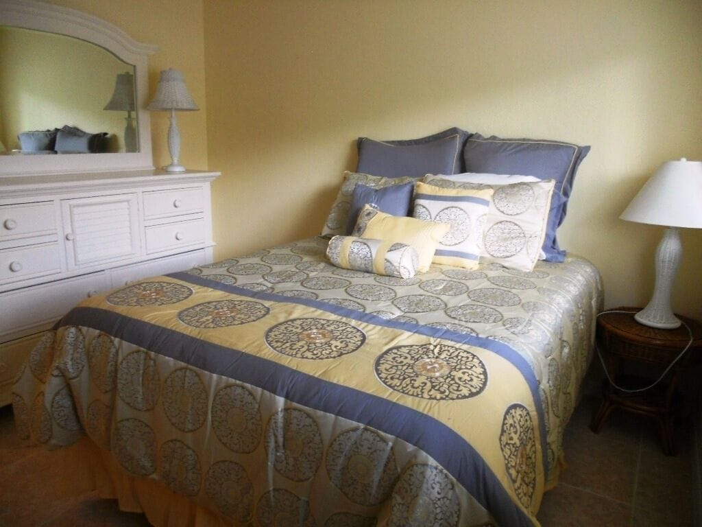 A bedroom with a bed, a dresser, a lamp, and a mirror.