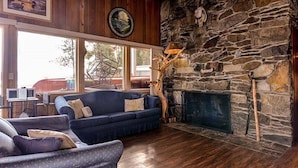 A cozy living room with a stone fireplace, a blue sofa, and a wooden floor.