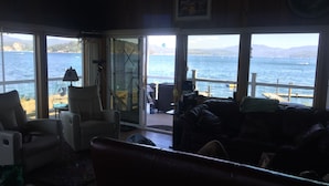 A cozy living room with a view of the sea, a large window, and a comfortable seating area.