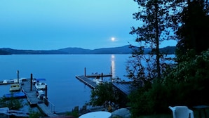A dock with boats, a pier, and a view of a calm lake with mountains in the background.