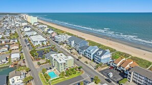 A coastal residential area with a beachfront, a swimming pool, and a road.