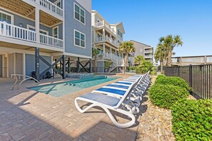 A pool area with lounge chairs and a clear sky.