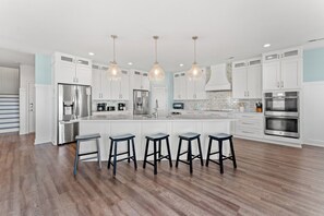 A modern kitchen with white cabinetry, stainless steel appliances, and a central island with bar stools.