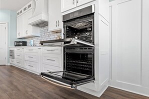 A kitchen with white cabinets, a microwave, and two ovens.