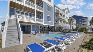 A poolside area with lounge chairs and a staircase leading to a building with multiple balconies.