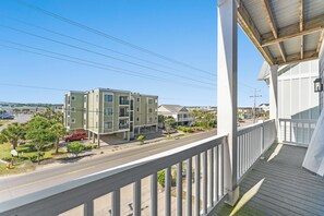 A residential building with a balcony, a street view, and a clear sky.