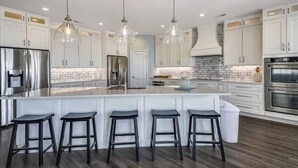 A modern kitchen with white cabinetry, stainless steel appliances, and a central island with bar stools.