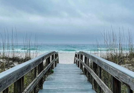 A wooden boardwalk leading to a beach with ocean views.