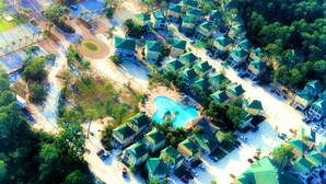 An aerial view of a residential area with houses, a swimming pool, and a road. - Slow Mo 17AD-Beautiful Beach Cottage @ the Purple Parrot Resort/Perdido Key FL (Pensacola)