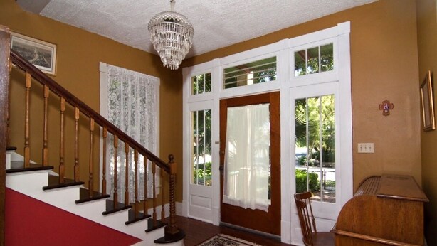 A staircase with wooden railings and a red carpet leading to a door with white curtains. - Beautiful Home in Historic Neighborhood
1/2 mile to Downtown and the Riverwalk (san antonio)