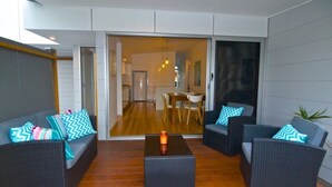 A modern living room with a sofa set, a coffee table, and a dining area visible through a sliding glass door. - Husky Getaway - Villa with Heated Plunge Pool (Huskisson)