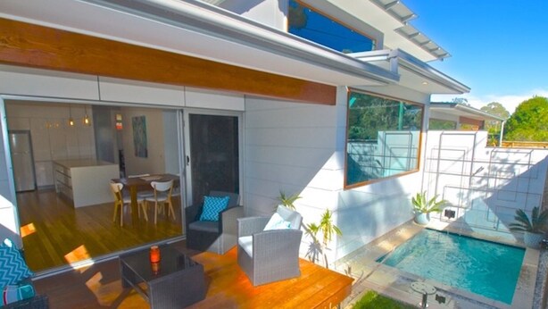 A modern house with a large patio area, a dining room, and a swimming pool. - Husky Getaway - Villa with Heated Plunge Pool (Huskisson)