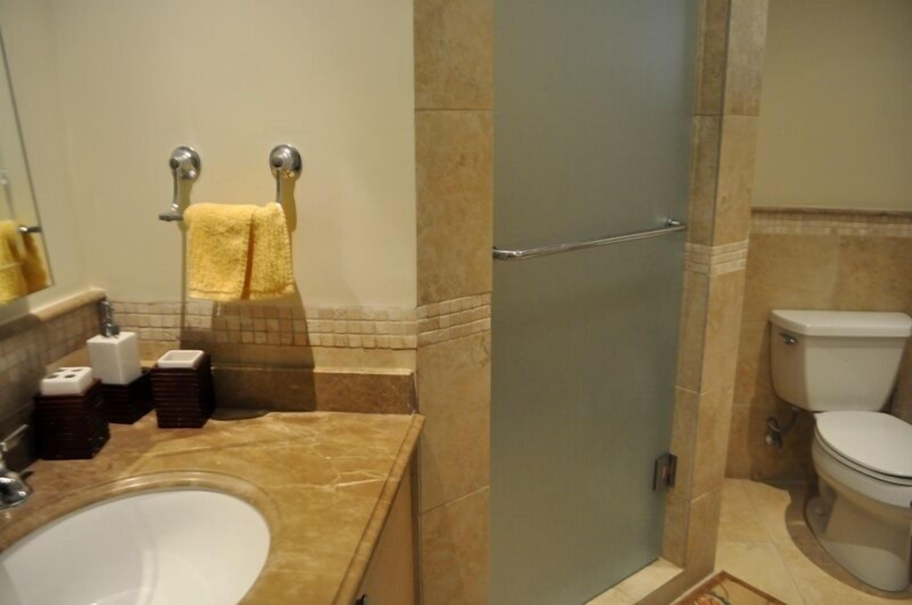 A bathroom with a bathtub, toilet, and a glass shower door.
