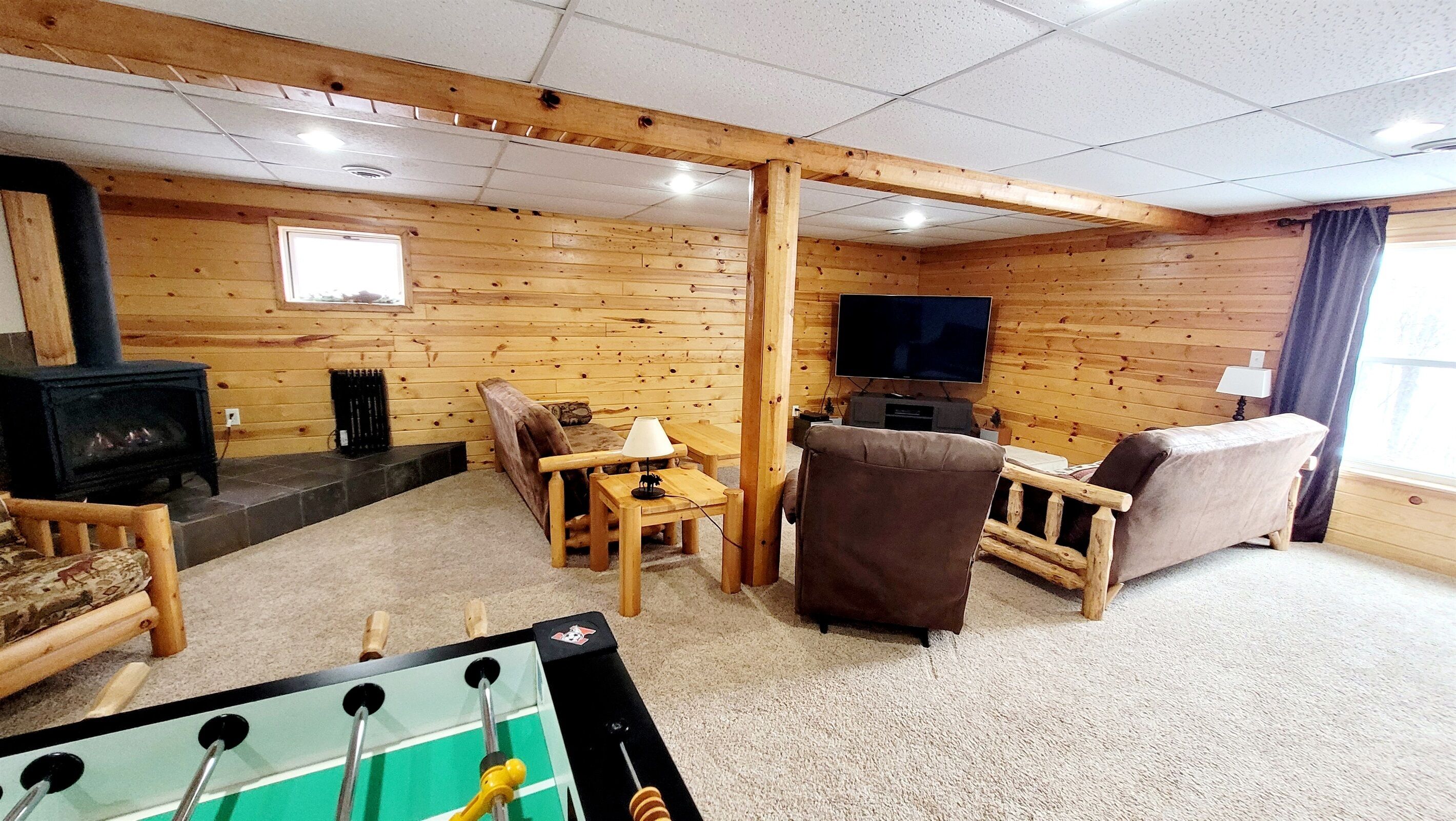 A cozy room with a wooden interior, a fireplace, a television, and a foosball table.