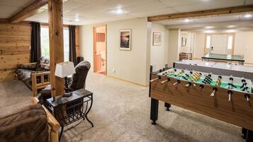 Une pièce chaleureuse avec un baby-foot, un canapé et une table de ping-pong.