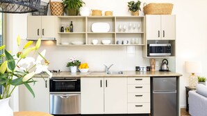 Une cuisine moderne avec des armoires blanches, des appareils en acier inoxydable et un plan de travail en bois.