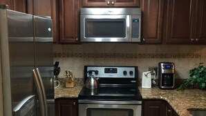 A kitchen with stainless steel appliances, including a refrigerator, microwave, stove, and oven.