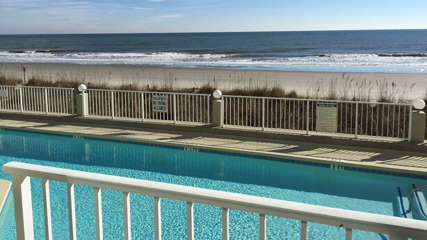 A pool with a view of the ocean and beach.