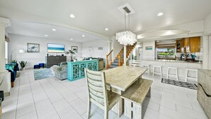 A spacious living area with a wooden dining table, a sofa, and a kitchen area with a bar. - 30 day Perfect “BEACHFRONT “ Getaway! Steps to the beach through the backyard (Laie)