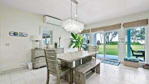 A dining area with a wooden table, chairs, and a hanging light fixture. - 30 day Perfect “BEACHFRONT “ Getaway! Steps to the beach through the backyard (Laie)