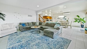 A modern living room with a sectional sofa, a round coffee table, and a blue patterned rug. - 30 day Perfect “BEACHFRONT “ Getaway! Steps to the beach through the backyard (Laie)