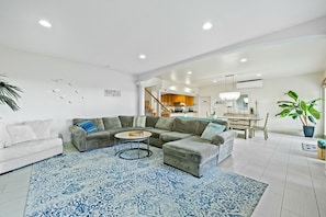 Uma sala de estar moderna com um sofá modular, uma mesa de centro redonda e um tapete azul estampado.