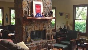 Ein gemütliches Wohnzimmer mit Kamin aus Stein, Ledermöbeln und Blick ins Grüne.