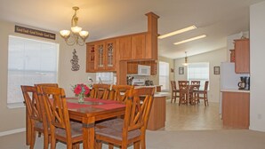 Una cocina amplia con armarios de madera, un comedor con mesa y sillas rojas, y una isla de cocina.