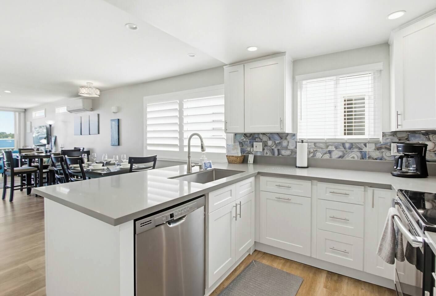 A modern kitchen with white cabinetry, a stainless steel dishwasher, and a coffee maker.