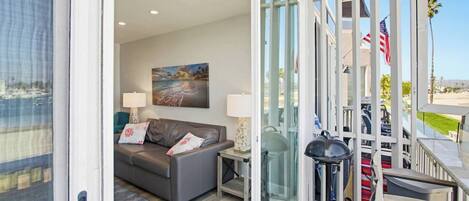 A modern living room with a sofa, a painting, and a view of the outdoors.
