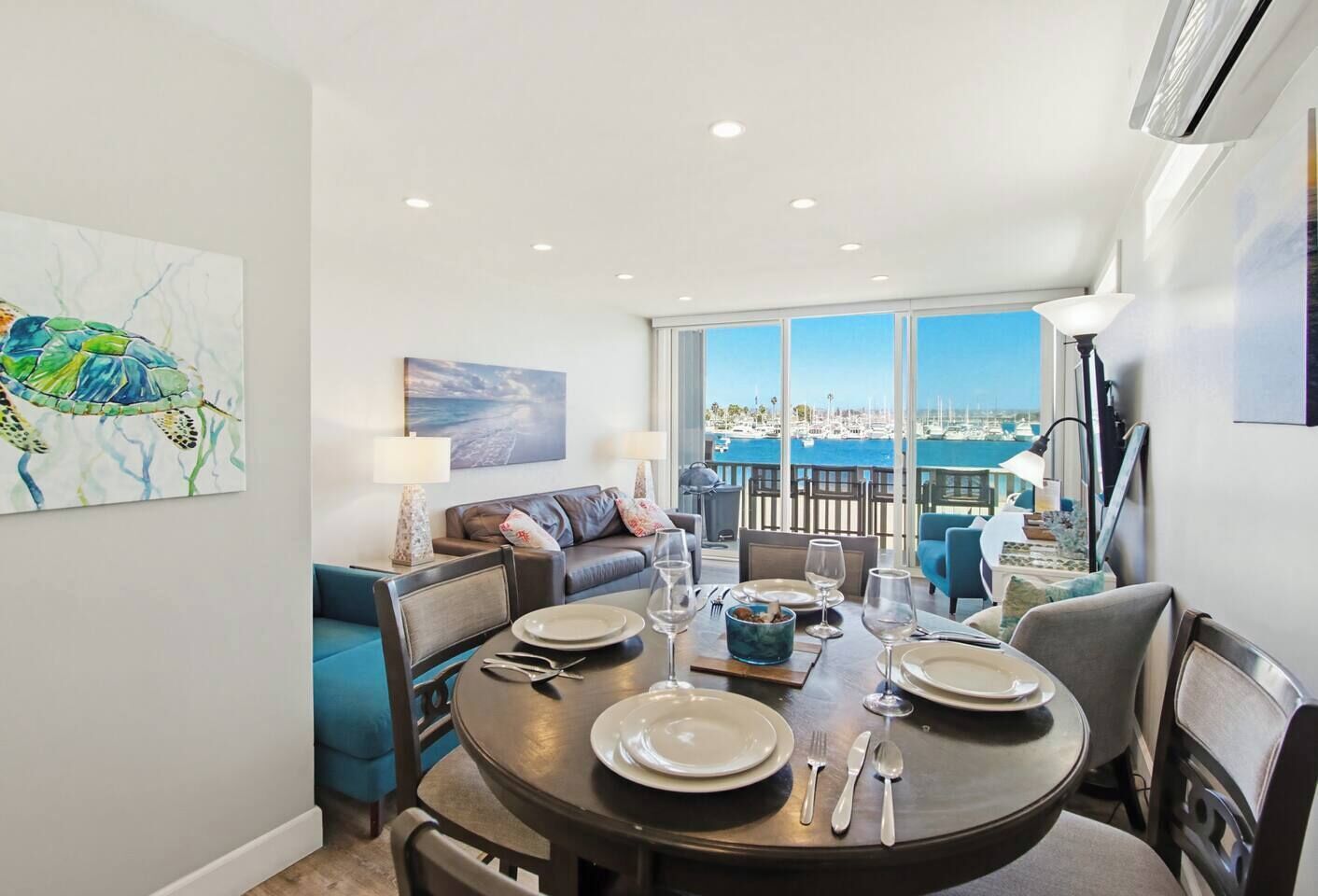 A dining area with a view of the marina, a sofa, and a table set for a meal.