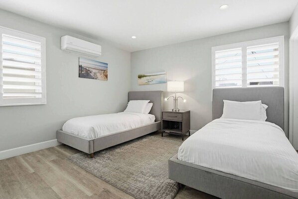 Un dormitorio con dos camas, una mesita de noche, una lámpara y un cuadro en la pared.