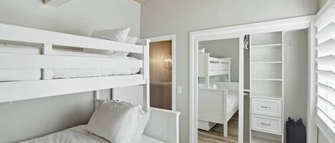 A bedroom with a bunk bed, a wardrobe, and a closet with shelves.