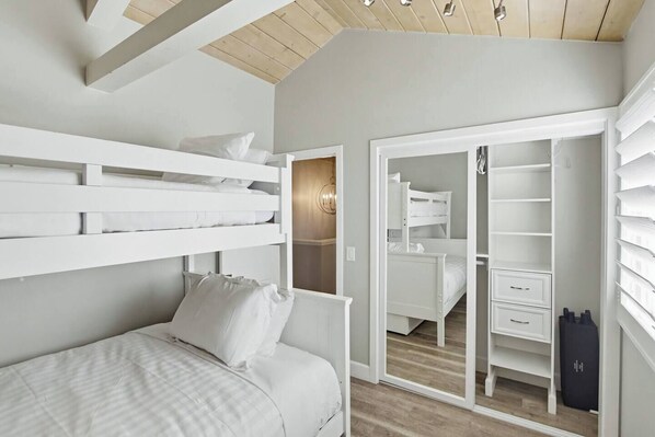 A bedroom with a bunk bed, a wardrobe, and a closet with shelves.