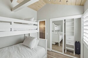 A bedroom with a bunk bed, a wardrobe, and a closet with shelves.