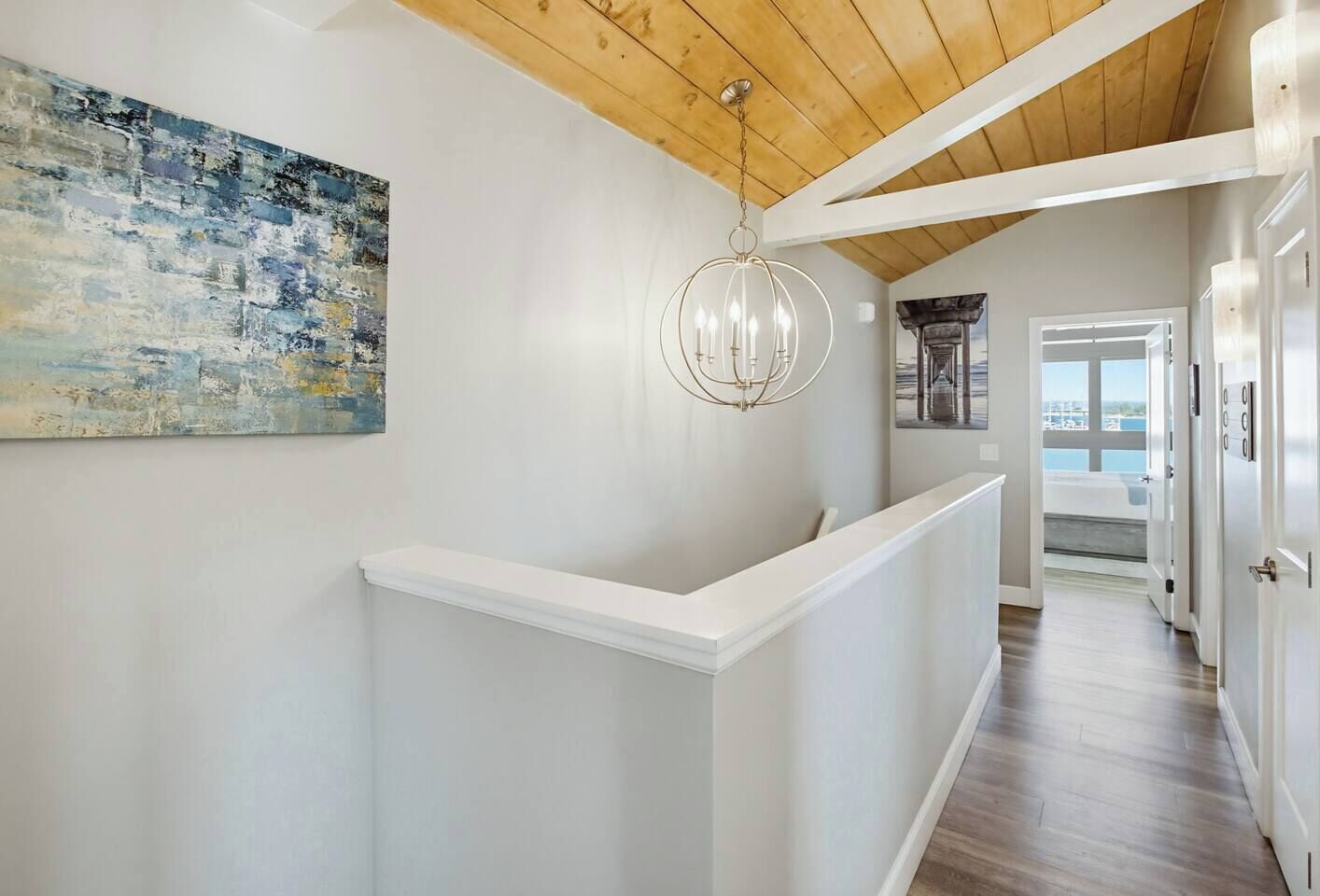 A hallway with a white reception desk, a modern chandelier, and a large abstract painting on the wall.