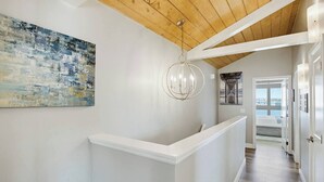 Ein Korridor mit einem weißen Empfangstresen, einer modernen Kronleuchter und einem großen, abstrakten Gemälde an der Wand.