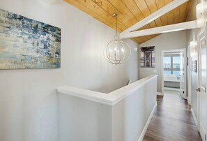 A hallway with a white reception desk, a modern chandelier, and a large abstract painting on the wall.