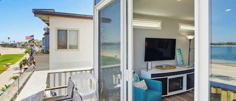 Een balkon met een witte reling, een blauwe bank en een flatscreen televisie.