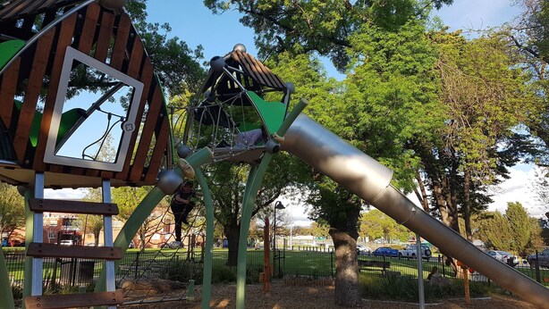 A playground with a climbing structure and a slide.
