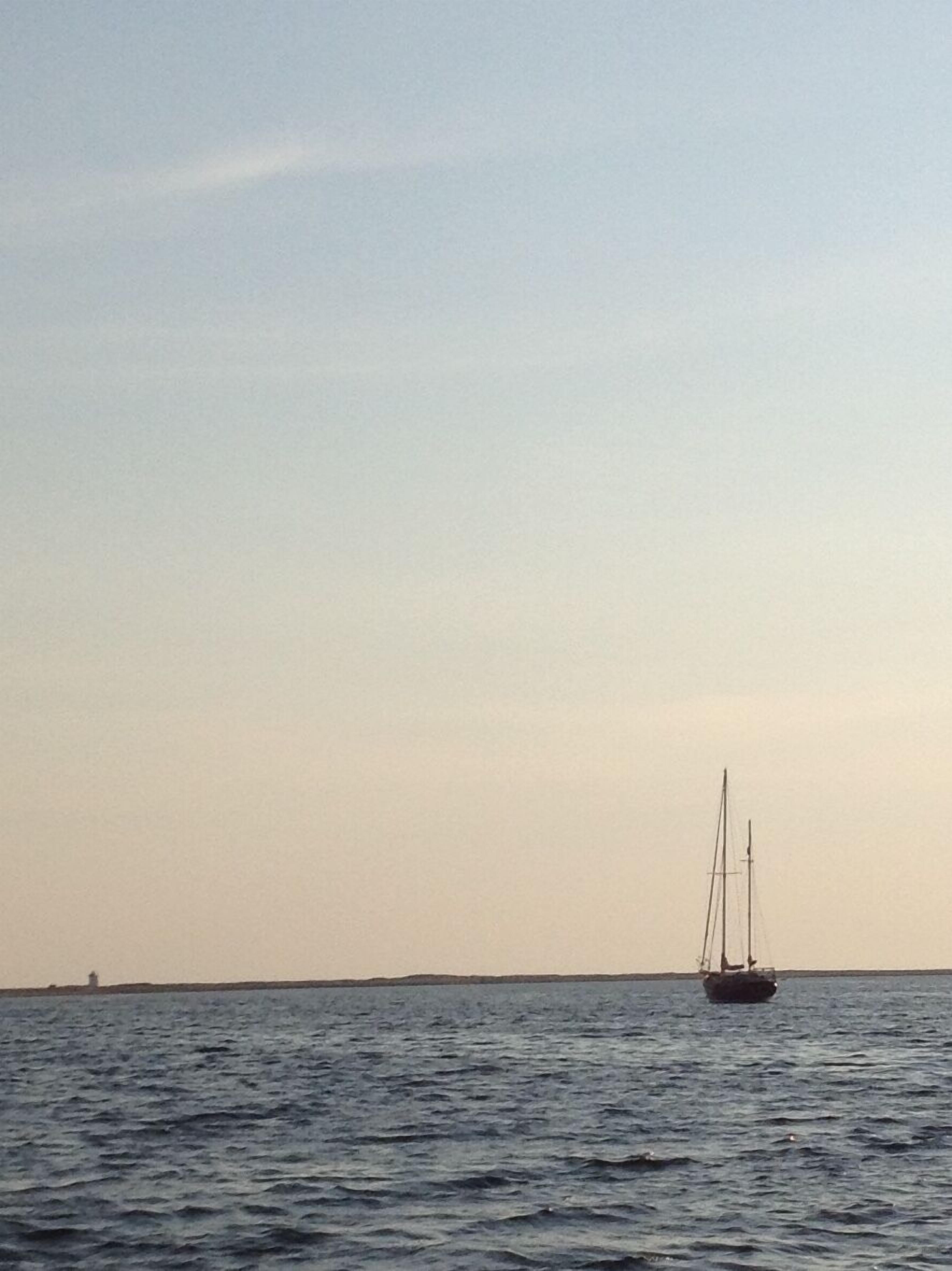 Ein ruhiges Meer mit einem Segelboot in der Ferne.