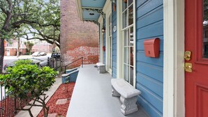 A building with a red door, a mailbox, and a bench on the porch. - Camelback Guest House (New Orleans)