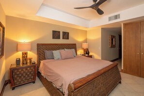 A bedroom with a large bed, two bedside lamps, a ceiling fan, and a wooden wardrobe. - 10th Floor Beachfront Luxury Condo Bayview Grand (Ixtapa)
