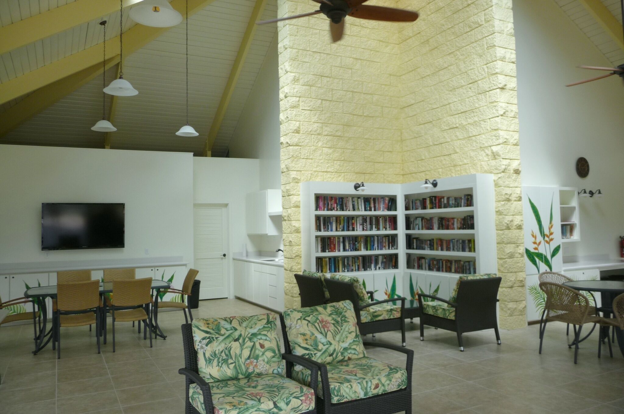 A spacious indoor area with a high ceiling, a large bookshelf, and several seating arrangements.