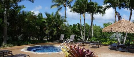 A pool area with lounge chairs and a thatched umbrella.