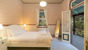 A bedroom with a bed, bedside lamps, a window with curtains, and a view of greenery outside. - Historic 1885 Blue Mountains Retreat | Sleeps 12 | 6 Bdrms | Free EV Charging (Wentworth Falls)